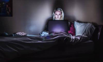 Woman using a laptop in bed at night